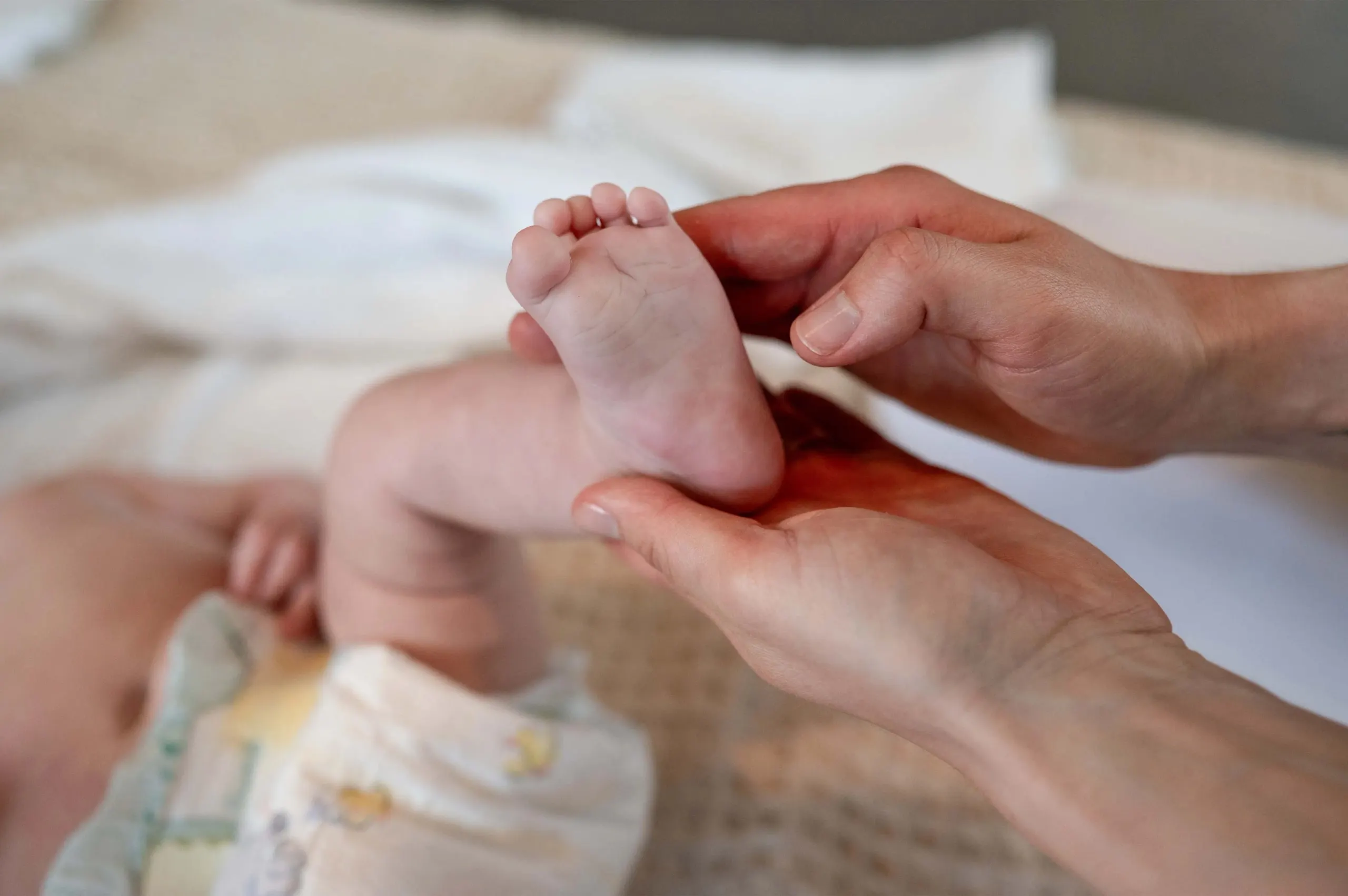 Eine Hand hält behutsam den Fuss eines Babys