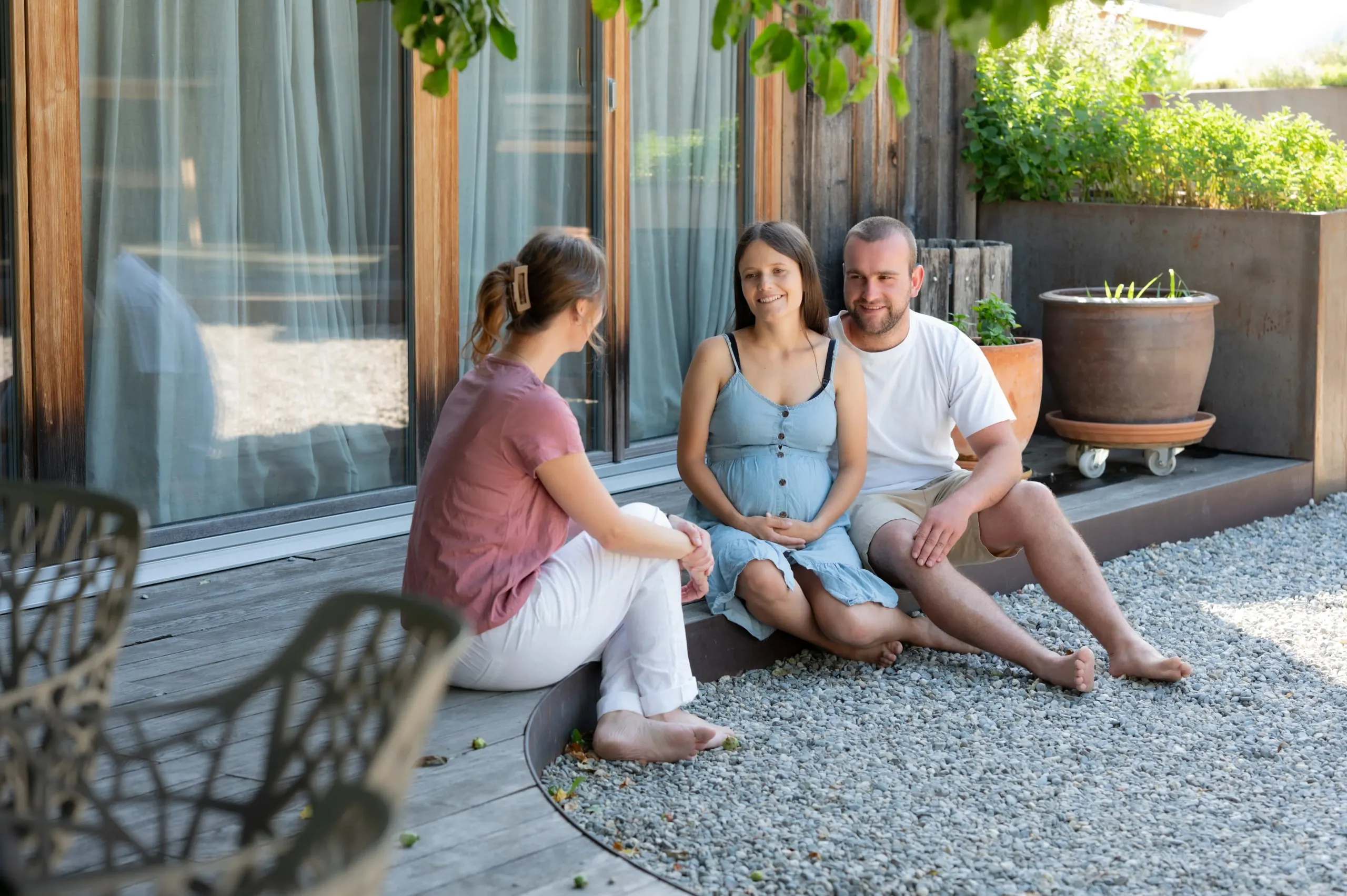 Rahel Tischhauser im Gespräch mit einem werdenden Elternpaar auf einer sonnigen Terrasse