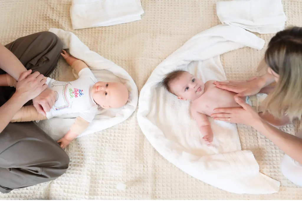 Mutter massiert die Beine ihres Babys auf einer hellen Decke